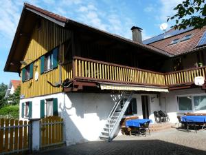 a yellow house with a staircase on the side of it at Allgäuer Taucherhof in Aitrang