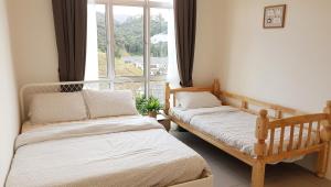 two beds in a room with a large window at Penthouse - Secret Garden de Cameron, Night Market in Tanah Rata