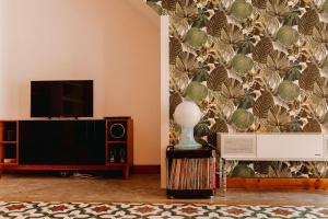 a living room with a tv and a wall with a wallpaper at La Casona Beach House in Valencia