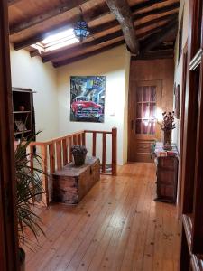 a living room with a wooden floor and a car painting on the wall at La Casa de las rocas - Ribeira Sacra in Rubiacós