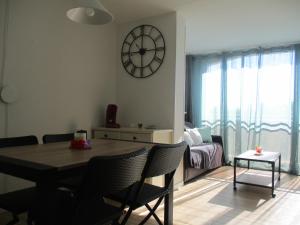 un soggiorno con un tavolo e un orologio a parete di Appartement En Bord De Mer avec piscine a Saint-Cyprien