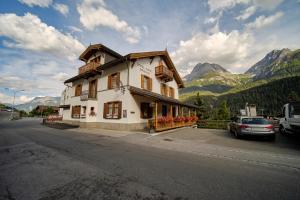 - un bâtiment sur le côté d'une rue avec des montagnes dans l'établissement Garni Alpenrose - Grusaida, à Scuol