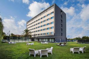 a building with white tables and chairs in the grass at AZZ Valencia Táctica Hotel in Paterna