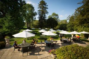 a group of people sitting at tables with umbrellas at The Inn at Fossebridge in Chedworth