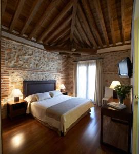 sypialnia z dużym łóżkiem i ceglaną ścianą w obiekcie El Pontifical w mieście Los Santos de la Humosa