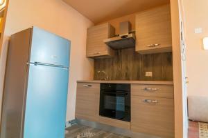 a kitchen with a blue refrigerator and wooden cabinets at Badiula Flat in Lentini