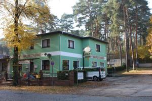 ein grün-weißes Gebäude mit einem Van vor dem Haus in der Unterkunft Waldrestaurant & Hotel in Rangsdorf