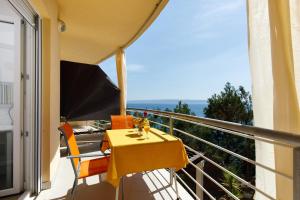 a yellow table and chairs on a balcony with a view at Ark Beach Apartments in Split