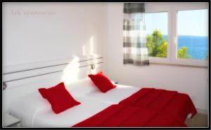 a white bed with red pillows in a room with a window at Ark Beach Apartments in Split