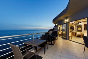 a balcony with tables and chairs and the ocean at night at Ark Beach Apartments in Split