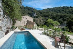 a swimming pool in front of a house with a mountain at La Ressence Luberon in Bonnieux