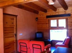 a living room with red chairs and a television at La Cicuarala in Guaso