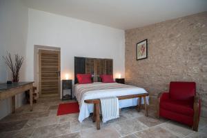 a bedroom with a bed and a red chair at La Ressence Luberon in Bonnieux