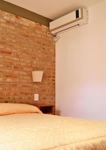 Un dormitorio con una pared de ladrillo y una cama en Complejo Sierras Blancas en Las Grutas