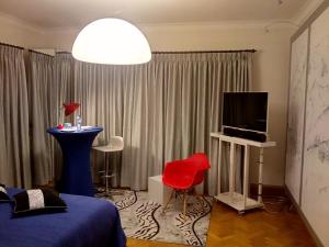 um quarto com uma cama, uma televisão e uma cadeira vermelha em La Pastorale Brussels Expo em Wemmel