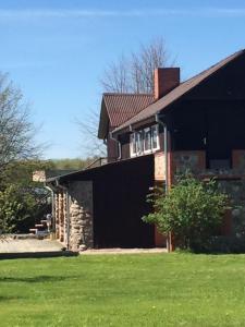 een groot zwart huis met een grasveld bij Guest House Pilsētnieki in Slampe