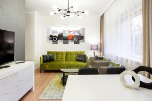 a living room with a green couch and a tv at Luxury for everyone - Hills Park Lux Apartments 2 in Vilnius