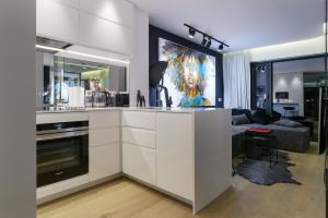 a kitchen with white cabinets and a living room at Andersia Park in Poznań