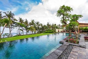 an infinity pool with palm trees and a house at Bali Natha Beach Front in Canggu