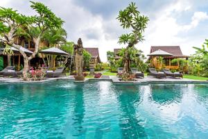 a pool at a resort with chairs and a fountain at Bali Natha Beach Front in Canggu