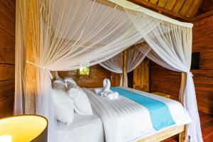a bedroom with a canopy bed with white pillows at Bali Natha Beach Front in Canggu