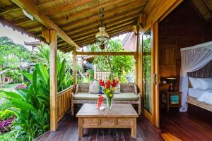 a porch with a bed and a table with flowers on it at Bali Natha Beach Front in Canggu