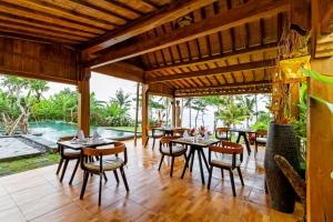 a dining room with tables and chairs and a pool at Bali Natha Beach Front in Canggu