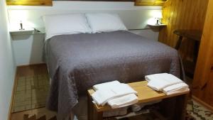 a bed in a room with two towels on a table at Chalés Lauterbrunnen in Monte Verde