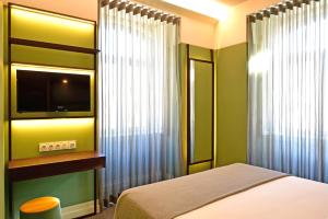 Schlafzimmer mit einem Bett, einem TV und einem Fenster in der Unterkunft My Story Hotel Augusta in Lissabon