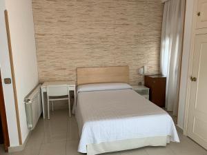 Dormitorio pequeño con cama, mesa y silla en Hostal Cervantes en Valdemoro