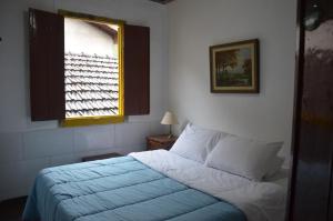 1 dormitorio con 1 cama con manta azul y ventana en Pouso da Passagem B&B, en Mariana