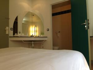 a bedroom with a bed and a sink and a mirror at ibis Budget Caen Centre Gare in Caen
