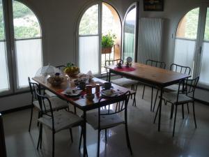 een eetkamer met 2 tafels, stoelen en ramen bij B&B Nelly G in Carbuta