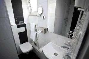 a bathroom with a sink and a toilet and a mirror at Hotel Savoy Bonn in Bonn