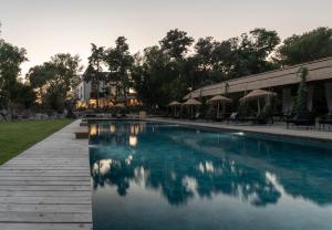 a swimming pool with chairs and umbrellas next to a building at Domaine Tarbouriech, Demeure & Spa in Marseillan