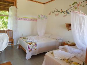 Un dormitorio con dos camas y una ventana. en El Eden Bungalows, en Mazunte