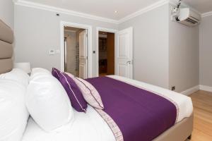 a bedroom with a bed with purple and white pillows at One bedroom Hyde Park Apartment in London