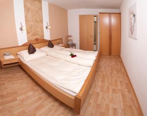 a large white bed in a room with wooden floors at Apart Sunnbichl in Nauders