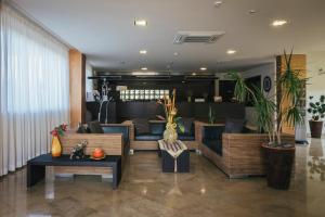 a living room with couches and tables and plants at Hotel Costa Azul in Balestrate