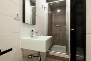 a white bathroom with a sink and a shower at Putxet by gaiarooms in Barcelona