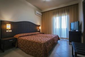 a hotel room with a bed and a television at Hotel Costa Azul in Balestrate