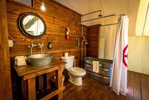 a bathroom with a sink and a toilet and a mirror at Conestoga Ranch Glamping Resort in Garden City