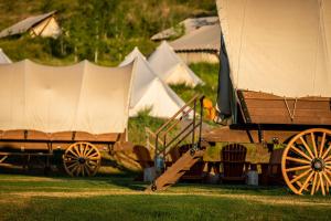 a group of tents in a field with a wagon at Conestoga Ranch Glamping Resort in Garden City