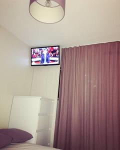 レ・サ​​ーブル・ドロンヌにあるLes Libellulesのカーテン付きのベッドルーム、壁掛けテレビが備わります。