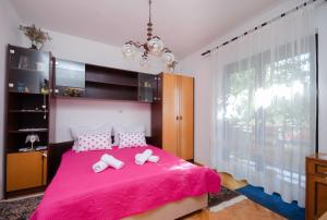 a bedroom with a pink bed with two towels on it at Apartment Katarina in Crikvenica