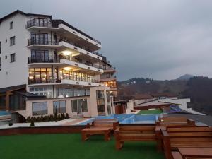 a large white building with a swimming pool and benches at Ogi & Una Premijer 42 in Kopaonik