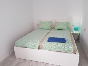 ein weißes Schlafzimmer mit einem großen weißen Bett mit blauer Bettwäsche in der Unterkunft Apartamento Adeje II in Adeje