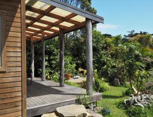 a wooden pergola on a deck in a garden at Omau Retreat in Cape Foulwind