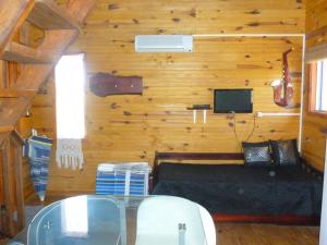 Habitación con cama, TV y mesa. en Excelente Cabaña Cumbre del Diablo 2, en Punta del Diablo