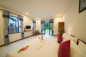 a room with a large white bed with red pillows at An Bang Star Homestay in Hoi An